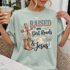 Woman wearing Raised on Dirt Roads & Jesus Christian Comfort Colors T-Shirt in Bay